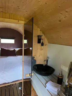 a bathroom with a sink and a bed in a room at Twee heerlijke Boomhutten in de natuur, Amsterdam in Nigtevecht