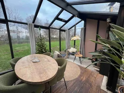 a conservatory with a wooden table and chairs at Twee heerlijke Boomhutten in de natuur, Amsterdam in Nigtevecht