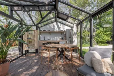 a greenhouse with a table and a kitchen in it at Twee heerlijke Boomhutten in de natuur, Amsterdam in Nigtevecht