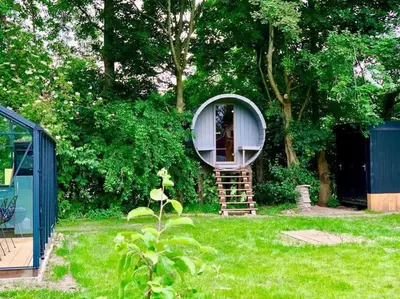 a small round house in a yard with a tree at Twee heerlijke Boomhutten in de natuur, Amsterdam in Nigtevecht