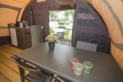 a table in a tent with some flowers on it at Glamping at the water, close to Amsterdam in Aalsmeer