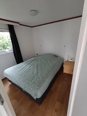 a bedroom with a bed in a small room at Chalet dichtbij zee en duinen in Heemskerk