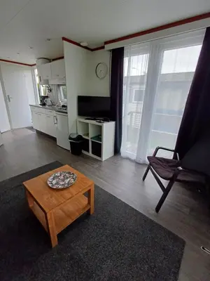 a living room with a table and a chair at Chalet dichtbij zee en duinen in Heemskerk