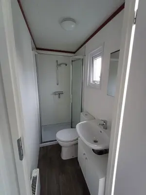 a white bathroom with a toilet and a sink at Chalet dichtbij zee en duinen in Heemskerk