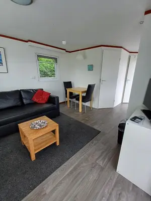 a living room with a couch and a table at Chalet dichtbij zee en duinen in Heemskerk