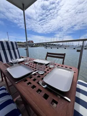 a wooden table with plates and glasses and a bridge at Oktopus-Lofts - Houseboat in Lelystad