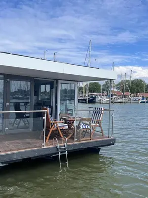 a boat with two chairs and a table on the water at Oktopus-Lofts - Houseboat in Lelystad