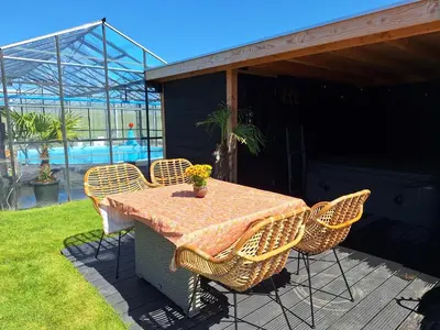 a table and chairs on a patio with a pool at Chalet aan zee in Noordwijk aan Zee