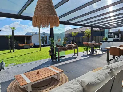 a patio with a couch and a bench and a table at Chalet aan zee in Noordwijk aan Zee