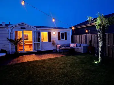 a house with a couch on a deck at night at Chalet aan zee in Noordwijk aan Zee