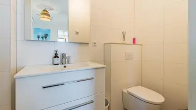a white bathroom with a sink and a toilet at Villa Sea breeze in Bergen aan Zee