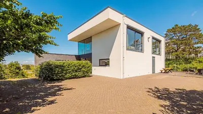 a white house with a large window at Villa Sea breeze in Bergen aan Zee