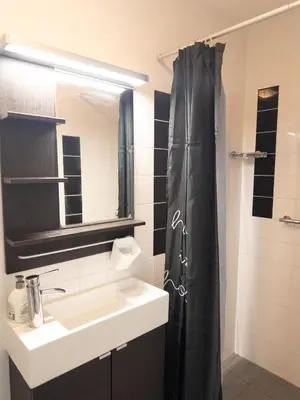 a bathroom with a sink and a black shower curtain at De Schelp 86, Garden and Free parking in Zandvoort