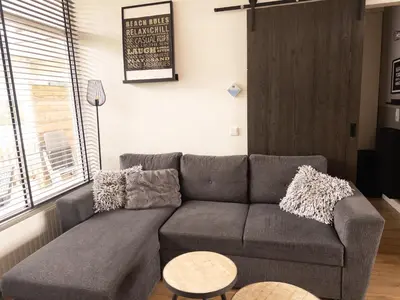 a living room with a couch and a table at De Schelp 86, Garden and Free parking in Zandvoort