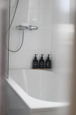 a shower with three black bottles on a shelf at Studio Jordaan Amsterdam City Centre in Amsterdam