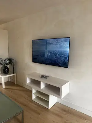 a white living room with a tv on a wall at Studio Jordaan Amsterdam City Centre in Amsterdam