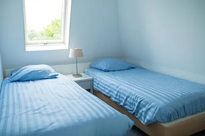 two twin beds in a room with a window at Tulp en Zee in Noordwijk