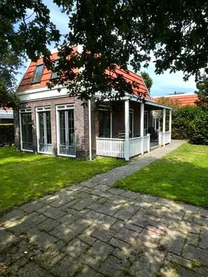 a brick house with a red roof and a yard at Tulp en Zee in Noordwijk