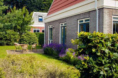 a garden with a table and chairs and purple flowers at Tulp en Zee in Noordwijk