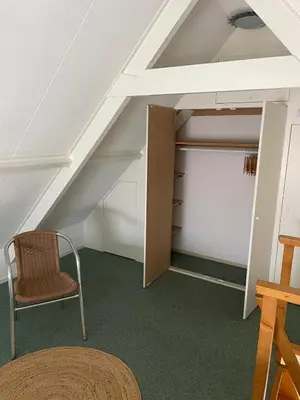 an attic room with a chair and a closet at Beachhouse De Dahlia in Noordwijk aan Zee