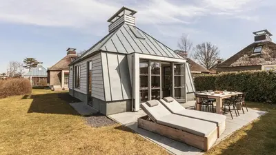 a small house with a white couch and a table at Dutchen Vakantiepark Duynvallei in Schoorl