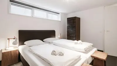 a bedroom with two beds with white sheets and a window at Dutchen Vakantiepark Duynvallei in Schoorl