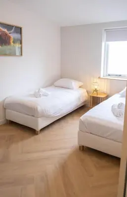 a bedroom with two beds and a window at Sint Adelbertus in Egmond-Binnen