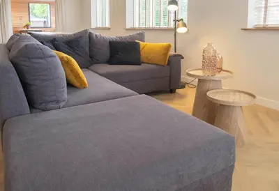 a living room with a blue couch and a table at Sint Adelbertus in Egmond-Binnen