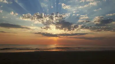 a sunset on the beach with the ocean and clouds at Sint Adelbertus in Egmond-Binnen
