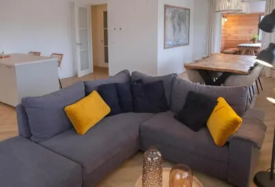 a living room with a blue couch with yellow pillows at Sint Adelbertus in Egmond-Binnen