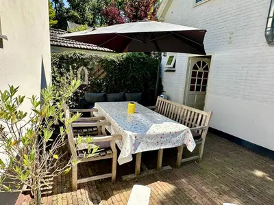 a table and chairs under an umbrella on a patio at Vakantiehuis Flori in Bergen