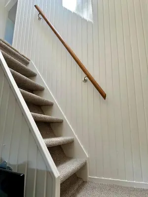 a staircase with a wooden rail next to a white wall at Vakantiehuis Flori in Bergen