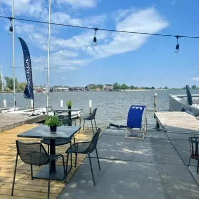 a table and chairs on a dock with the water at Houseboat Tomio near Amsterdam in Monnickendam
