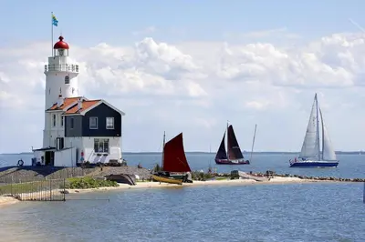 a lighthouse and sailboats on the water with boats at Houseboat Tomio near Amsterdam in Monnickendam