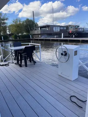 a wooden dock with a table and a grill on the water at Comfi Houseboat Maatrollie in Monnickendam close to Amsterdam in Monnickendam