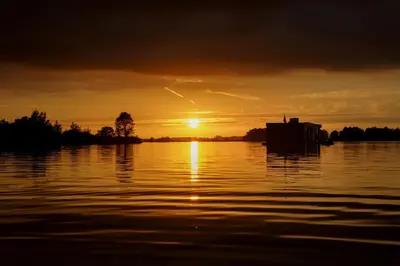a sunset over a body of water with the sun setting at Comfi Houseboat Maatrollie in Monnickendam close to Amsterdam in Monnickendam