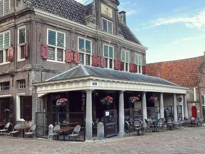 a building with chairs and tables in front of it at Comfi Houseboat Maatrollie in Monnickendam close to Amsterdam in Monnickendam