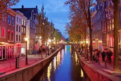 a canal in a city at night with people walking around at Comfi Houseboat Maatrollie in Monnickendam close to Amsterdam in Monnickendam