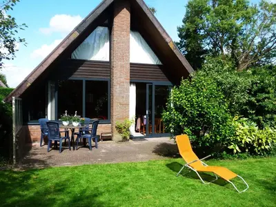 a house with a table and chairs in the grass at Bungalowpark in Nordholland in Opmeer