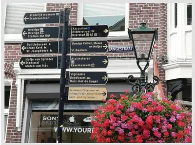a bunch of street signs on a pole with flowers at Bungalowpark in Nordholland in Opmeer