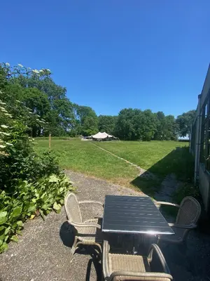 a picnic table and chairs with a field in the background at Het Huis van Bewustzijn in Limmen