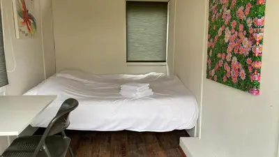a small bedroom with a bed with white sheets at Het Huis van Bewustzijn in Limmen