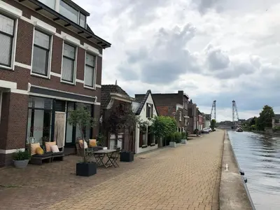 a brick street next to a river with buildings at B&B Boskoop in Boskoop