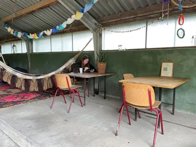 a woman sitting at a table with two chairs at Vintage caravan in old orchard at farm Huize Blokland in Hem