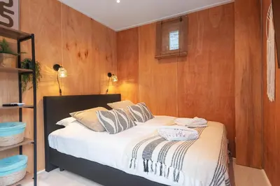 a bedroom with a bed with wood paneling at Beachhouse Rina - Free Parking in Zandvoort