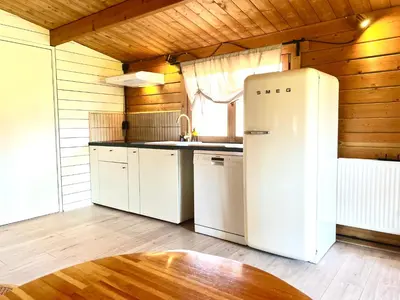 a kitchen with a white refrigerator and a table at Mediterranean style chalet with jacuzzi and garden near Amsterdam in Vijfhuizen