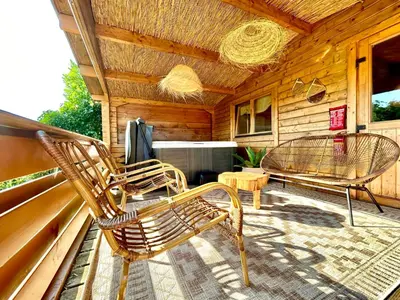 a porch with two chairs and a table on a cabin at Mediterranean style chalet with jacuzzi and garden near Amsterdam in Vijfhuizen