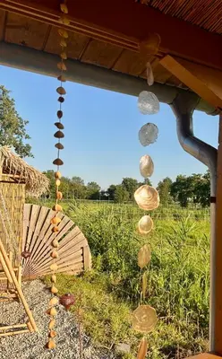 a view of a field with shells hanging from a porch at Mediterranean style chalet with jacuzzi and garden near Amsterdam in Vijfhuizen