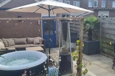 a hot tub in a backyard with an umbrella at Garden, Jacuzzi, bbq, city centre, 2 bedrooms in Alkmaar