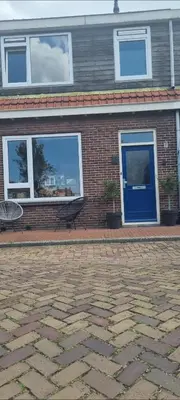 a brick building with a blue door and a bench at Garden, Jacuzzi, bbq, city centre, 2 bedrooms in Alkmaar